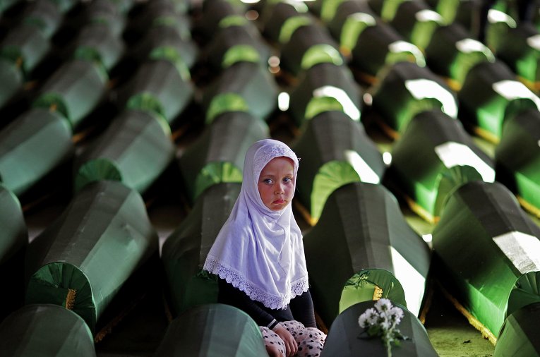 Девочка возле гроба своего родственника, одного из 173 выявленных жертв в результате резни в 1995 году в Сребренице, в Мемориальном центре Потокари. Архивное фото от 9 июля 2014