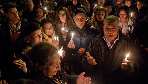 Тунисцы с зажженными свечами молятся у въездных ворот в музей Бардо, где десятки людей были убиты боевиками
