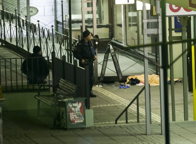 Полицейский стоит возле одной из жертв на месте стрельбы в Гетеборге