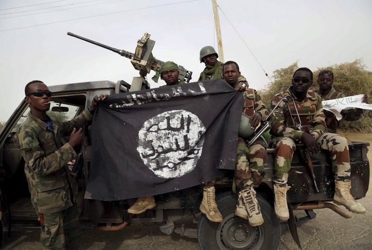 Нигерийские солдаты держат флаг Боко Харам, который они недавно захватили