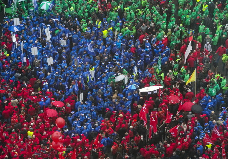 Протестующие в красных (социалисты), синих (либералы) и зеленых (христианские демократы) жилетах собираются в центре Брюсселя во время встречи профсоюзов 19 марта