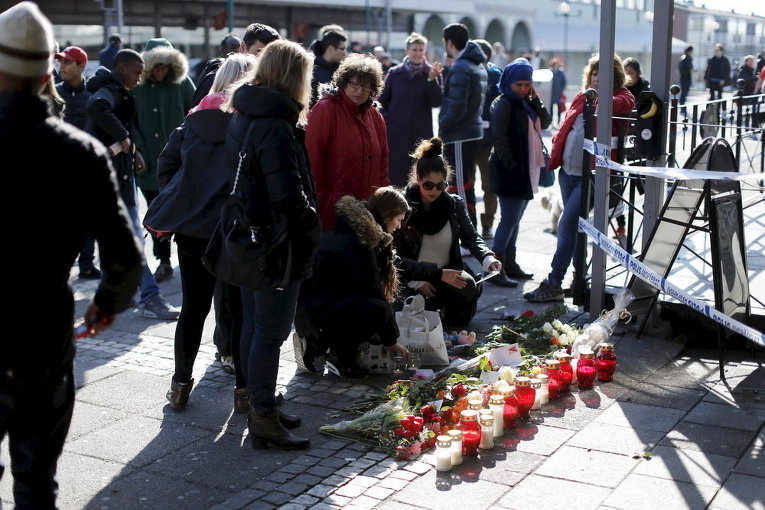 Люди возлагают цветы на месте стрельбы в Гетеборге