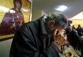Бедный человек молится перед обедом в столовой Православной Церкви в Афинах
