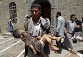 Мужчина несет тело ребенка, пострадавшего во время теракта в столице Йемена