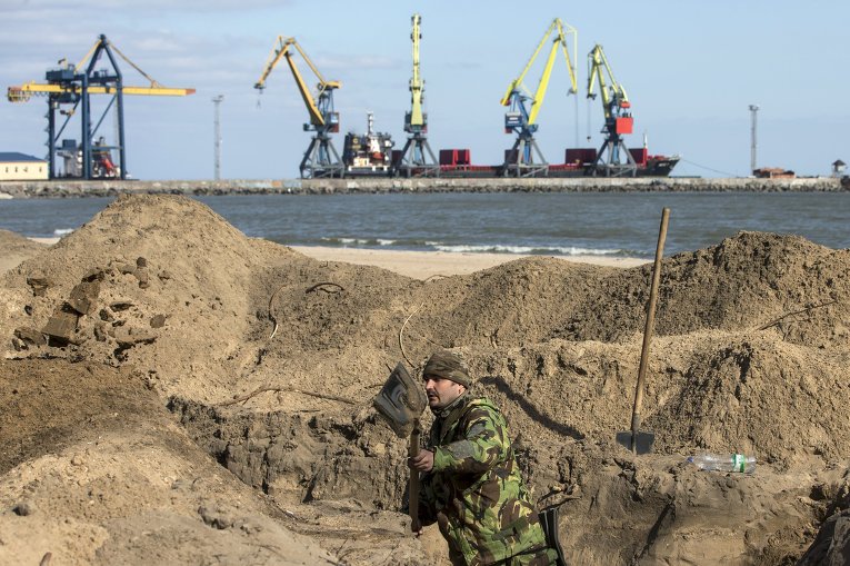 Украинский военнослужащий роет окопы на пляже в Мариуполе