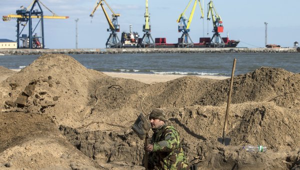 Украинский военнослужащий роет окопы на пляже в Мариуполе
