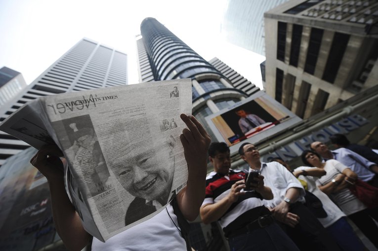 Мужчина читает газету, в которой напечатана статья о смерти автора сингапурского экономического чуда Ли Куан Ю, который умер на 92 году жизни