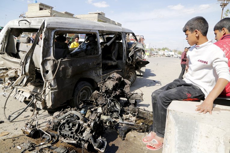 Иракские дети смотрят на сгоревший в результате теракта автомобиль в Багдаде