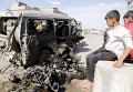 Иракские дети смотрят на сгоревший в результате теракта автомобиль в Багдаде