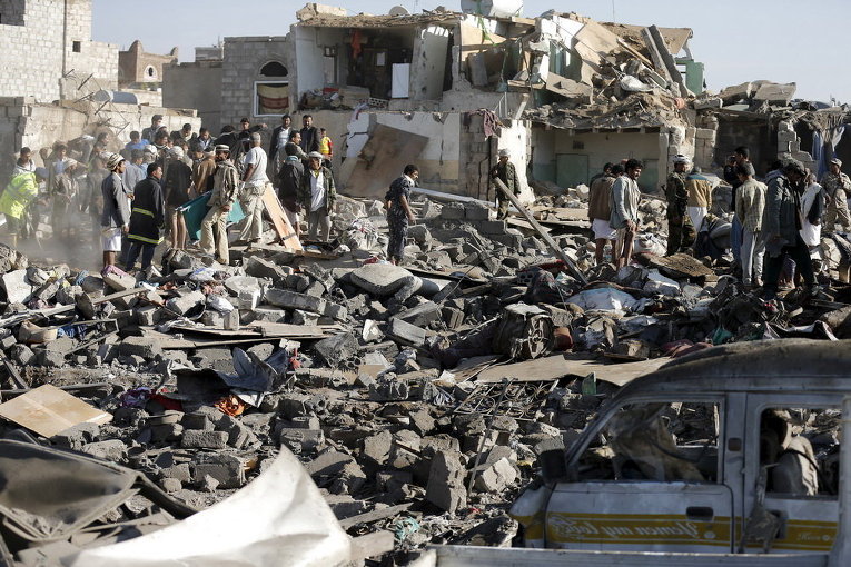 Работники гражданской обороны и люди ищут выживших под обломками домов, разрушенных авиаударами вблизи аэропорта Саны