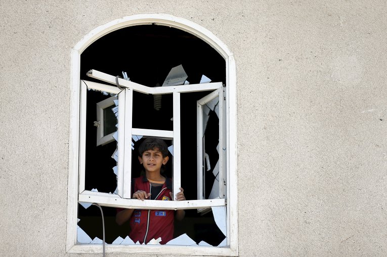 Маленький житель Йемена смотрит из окна своего разрушенного дома в результате военной операции коалиции