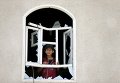 Маленький житель Йемена смотрит из окна своего разрушенного дома в результате военной операции коалиции