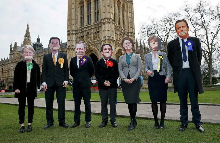 Активисты из Британской медицинской ассоциации в масках лидеров британских партий у здания парламента в центре Лондона