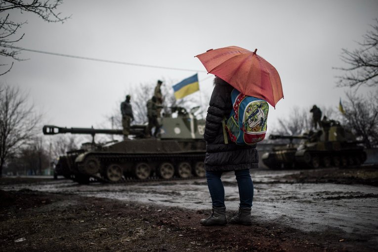 Школьница смотрит на технику украинских военных на окраине Донецка (4 марта 2015 года)