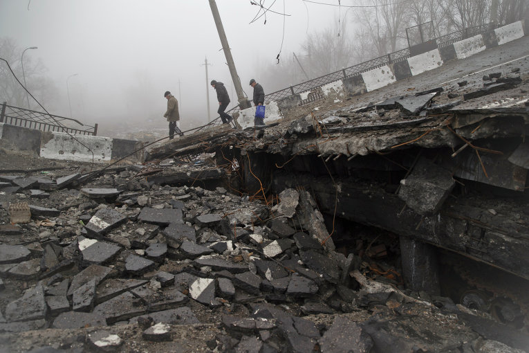 Мужчины переходят разрушенный мост, который упал на дорогу, ведущую к донецкому аэропорту (1 марта 2015 года)
