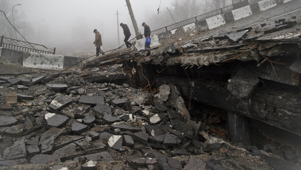 Мужчины переходят разрушенный мост, который упал на дорогу, ведущую к донецкому аэропорту (1 марта 2015 года)