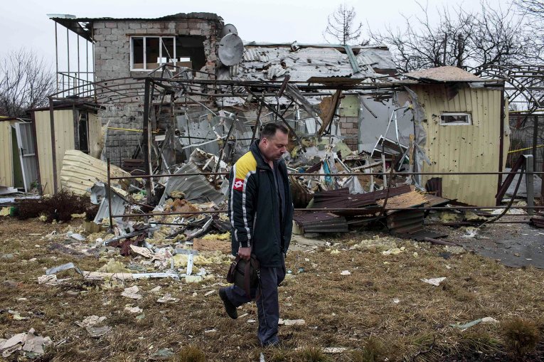 Мужчина проходит мимо разрушенного в результате обстрела дома в жилом районе Донецке (5 марта 2015 года)