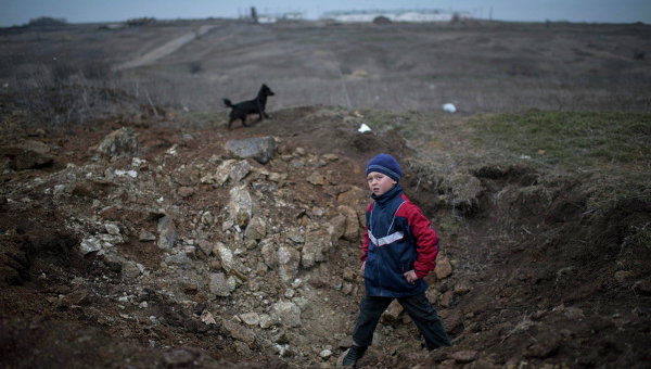 Мальчик стоит в воронке от взрыва в селе Чермалык на востоке Украины 26 февраля 2015 г