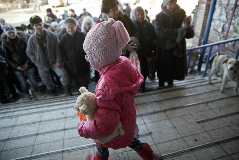 Маленькая девочка на фоне жителей Дебальцево, которые ждут доставку гуманитарной помощи, 23 Февраля 2015 г.