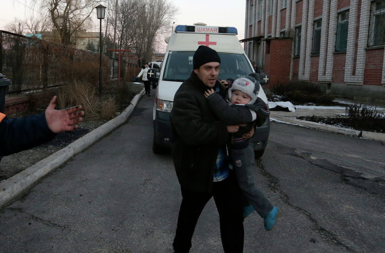 Мужчина несет ребенка после обстрела в Артемовске, 13 февраля 2015 г