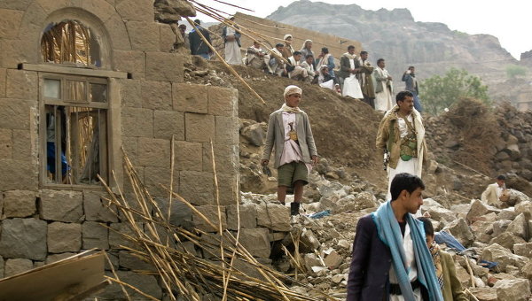 Йеменцы стоять среди развалин домов, разрушенных авиаударами в деревне недалеко от Саны