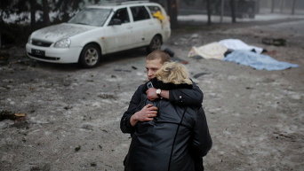 Мужчина успокаивает жену убитого местного жителя при обстреле в Донецке, 30 января 2015 г