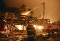 Пожарный наблюдает, как его коллеги пытаются потушить пожар на нефтехимическом заводе в Чжанчжоу