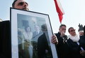Люди держат флаг Польши и фото покойного президента Леха Качиньского и его супруги Марии перед президентским дворцом во время церемонии, посвященной 5-летию со дня авиакатастрофы под Смоленском