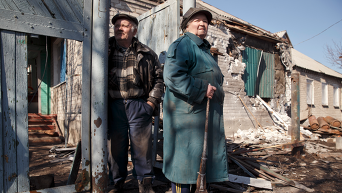 Пожилая пара смотрит на разрушения у своего дома в Дебальцево (9 марта 2015 года)