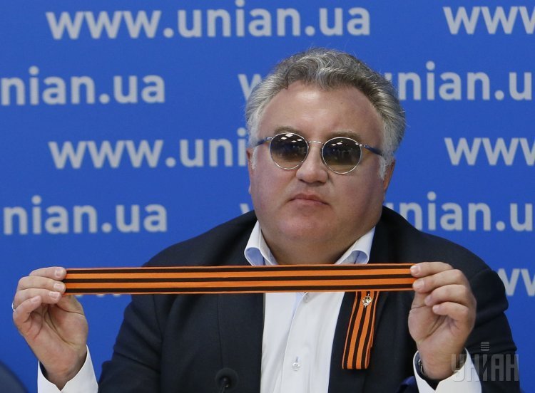 Олег Калашников во время пресс-конференции с георгиевской ленточкой в руках
