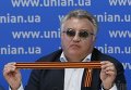 Олег Калашников во время пресс-конференции с георгиевской ленточкой в руках