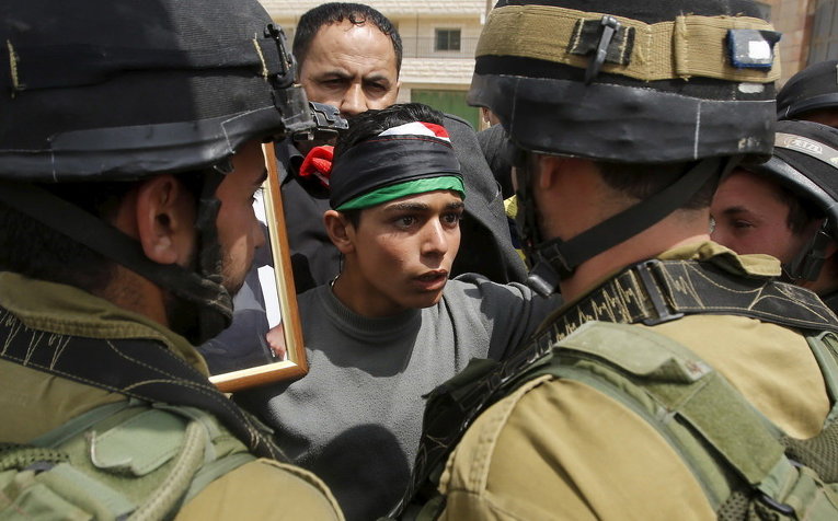 Палестинский демонстрант спорит с израильскими солдатами во время акции протеста по случаю Дня палестинских заключенных в селе Маасара 17 апреля 2015 года