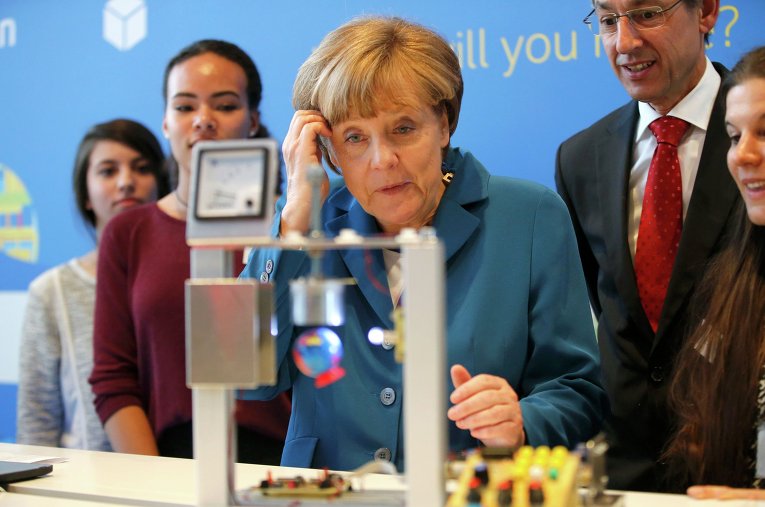 Канцлер Германии Ангела Меркель на встрече со студентами рассматривает технические изобретения