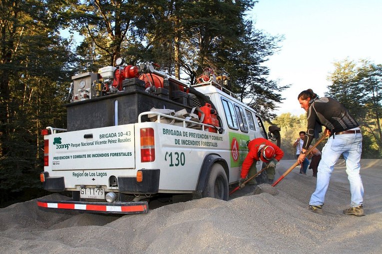 Волонтеры расчищают дорогу для пожарного автомобиля, который застрял в золе после извержения вулкана Кальбуко в Чили