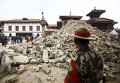 Непальский военнослужащий стоит перед разрушенным храмом