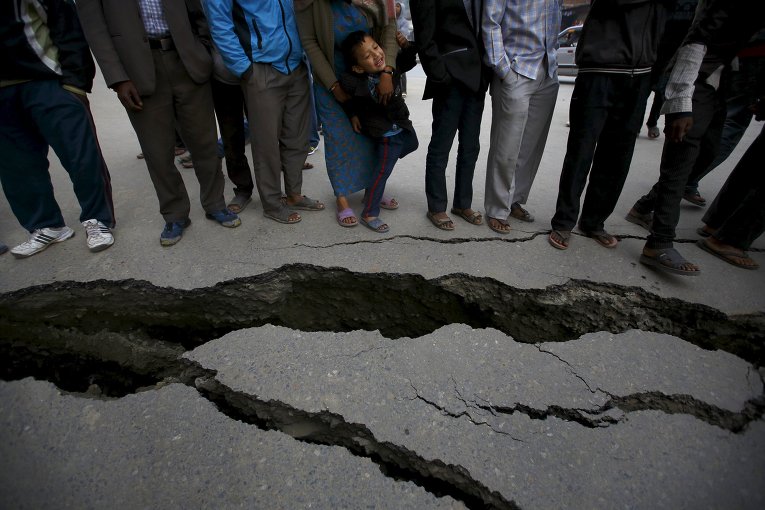 Люди стоят возле трещины в земле в результате землетрясения