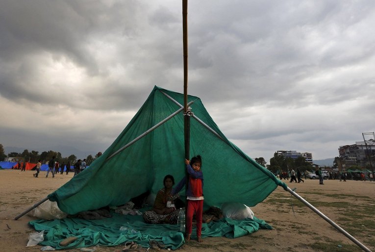 Непальская семья в импровизированном укрытии на открытой местности после землетрясения в Катманду