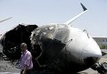 Представитель аэропорта проходит мимо самолета, разрушенного в результате авиаудара в Йемене
