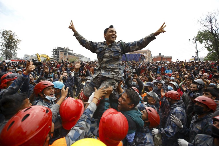 Члены непальской полиции несут их офицера, приветствуя после успешного спасения выжившего подростка