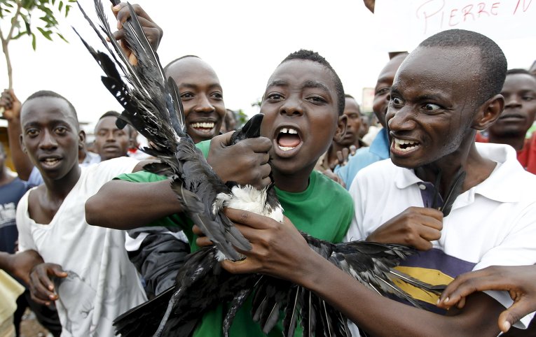 Протестующие несут мертвого ворона, скандируя антиправительственные лозунги в Бурундии