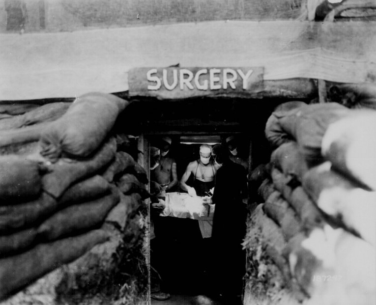 Хирург оказывает медицинскую помощь раненному во время боя на Бугенвиле, 13 декабря 1943 года.