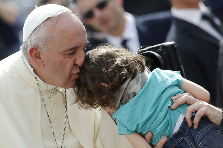 Папа Римский Франциск целует ребенка во время богослужения на площади Святого Петра в Ватикане