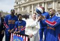 Папа Франциск улыбается члену баскетбольной команды Harlem Globetrotters на площади Святого Петра в Ватикане