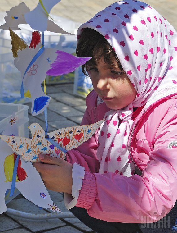 Девочка украшает бумажным голубем инсталляцию Голубь Памяти и Мира