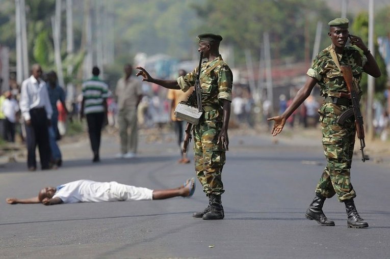 Участник акции протеста лежит не земле перед военным в Бурунди, где в городе Мусага проходят митинги против решения президента страны остаться на третий срок