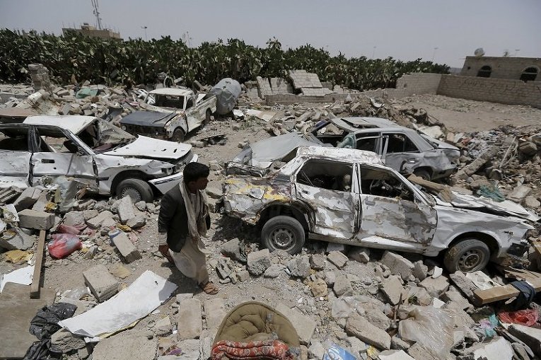 Мужчина идет на месте развалин в районе аэропорта Саны в Йемене