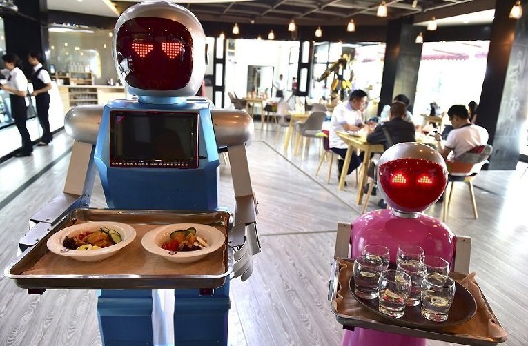 Пара роботов-официантов, которые обслуживают посететилей в кафе в китайском городе Циньхуа