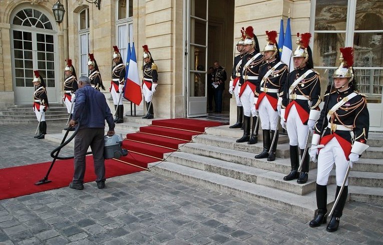 Служитель парижского отеля Hotel Matignon пылесосит красную дорожку перед встречей премьер-министра Мануэля Вальца с президентом .Сингапура Тони Таном