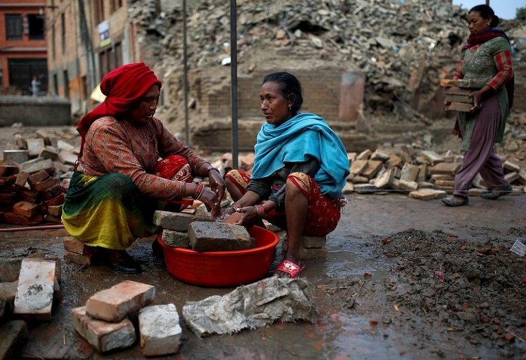 Женщины моют кирпичи, найденных на месте развалин после землетрясения в Непале