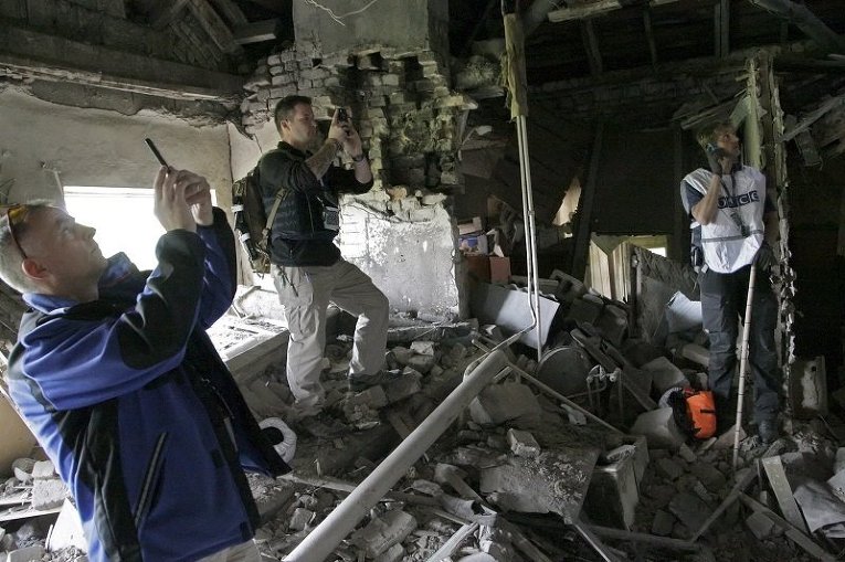 Наблюдатели ОБСЕ в Донецке фотографируют дом, разрушенный при обстреле